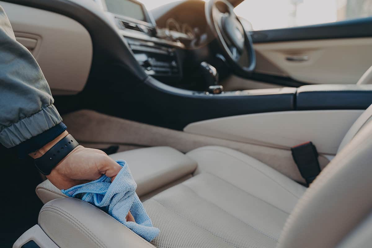 En hand som rengör bilens interiör med mikrofiberduk vid biltvätt