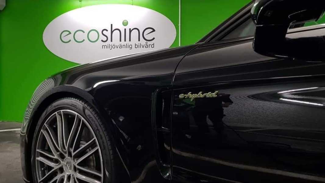 Skinande ren och svart bil efter utvändig rekond med ecoshine logotyp på en grön vägg bakom